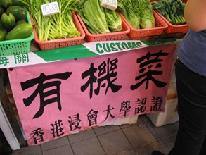 A banner stating "organic vegetables, certified by the Hong Kong Baptist University" displayed at the stall.