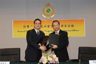 海關助理關長（情報及調查）譚耀強（右）與香港版權影印授權協會副主席李偉榮交換已簽訂的打擊「複製及分發罪行獎賞計劃」合作協議。