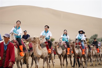 Members of “Customs YES” rode camels to the Mount Mingshashan and Crescent Moon-shaped Spring to appreciate the national desert landscape on July 11.