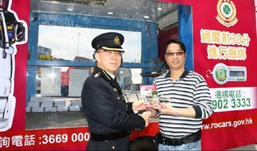 The Head of Land Boundary Command, Mr Ben Leung, today (March 21) presents a pamphlet to a driver during a ceremony to mark the operational launch of the mobile registration centre for the Road Cargo System (ROCARS).
