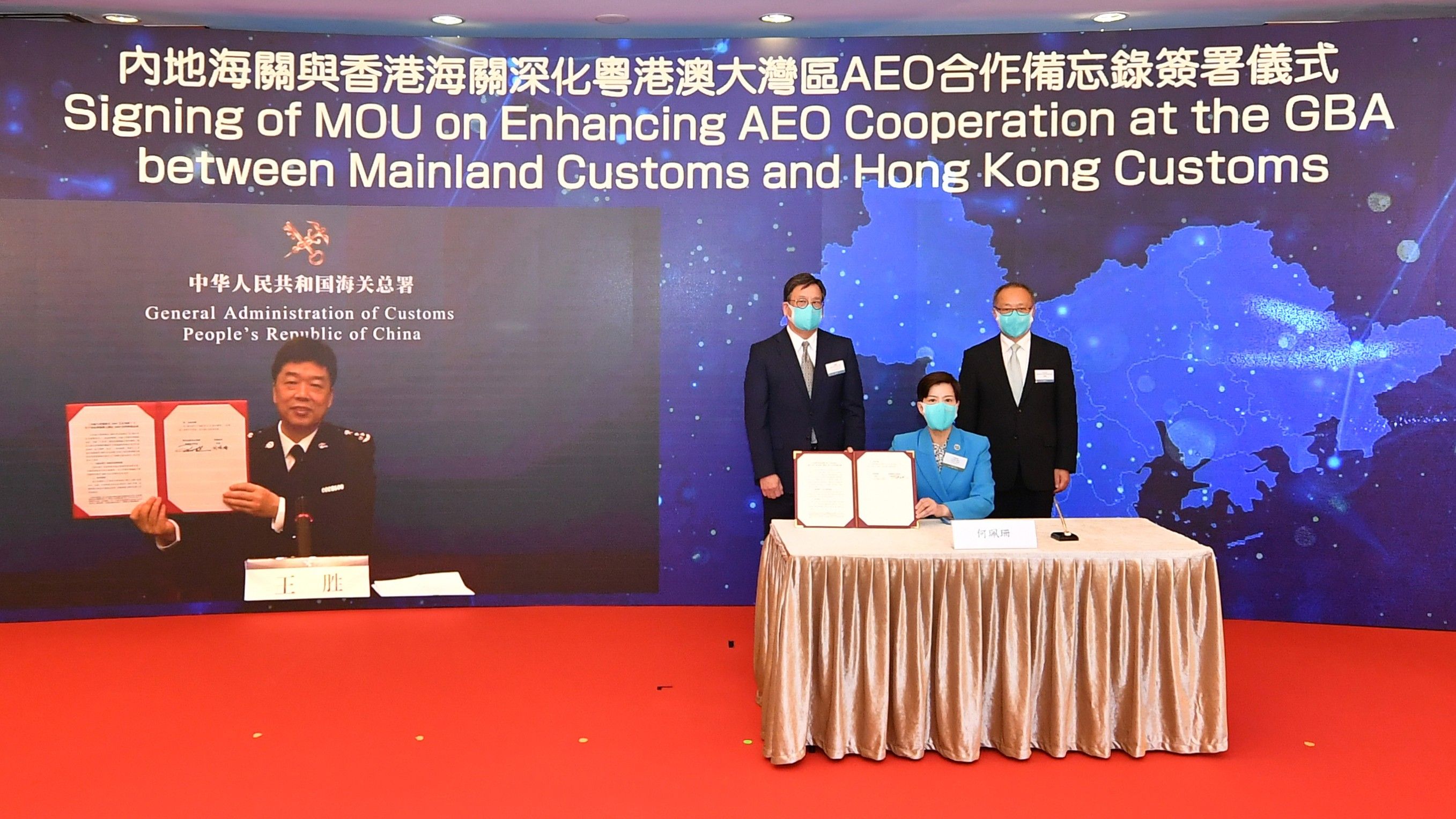 香港海關關長何珮珊（前排）與國家海關總署企業管理及稽查司司長王勝（螢幕上）簽署內地海關與香港海關關於深化粵港澳大灣區「認可經濟營運商計劃」合作備忘錄。簽署儀式在商務及經濟發展局局長丘應樺（後排左）和中聯辦經濟部副部長兼貿易處負責人劉亞軍（後排右）的見證下以視像形式舉行。