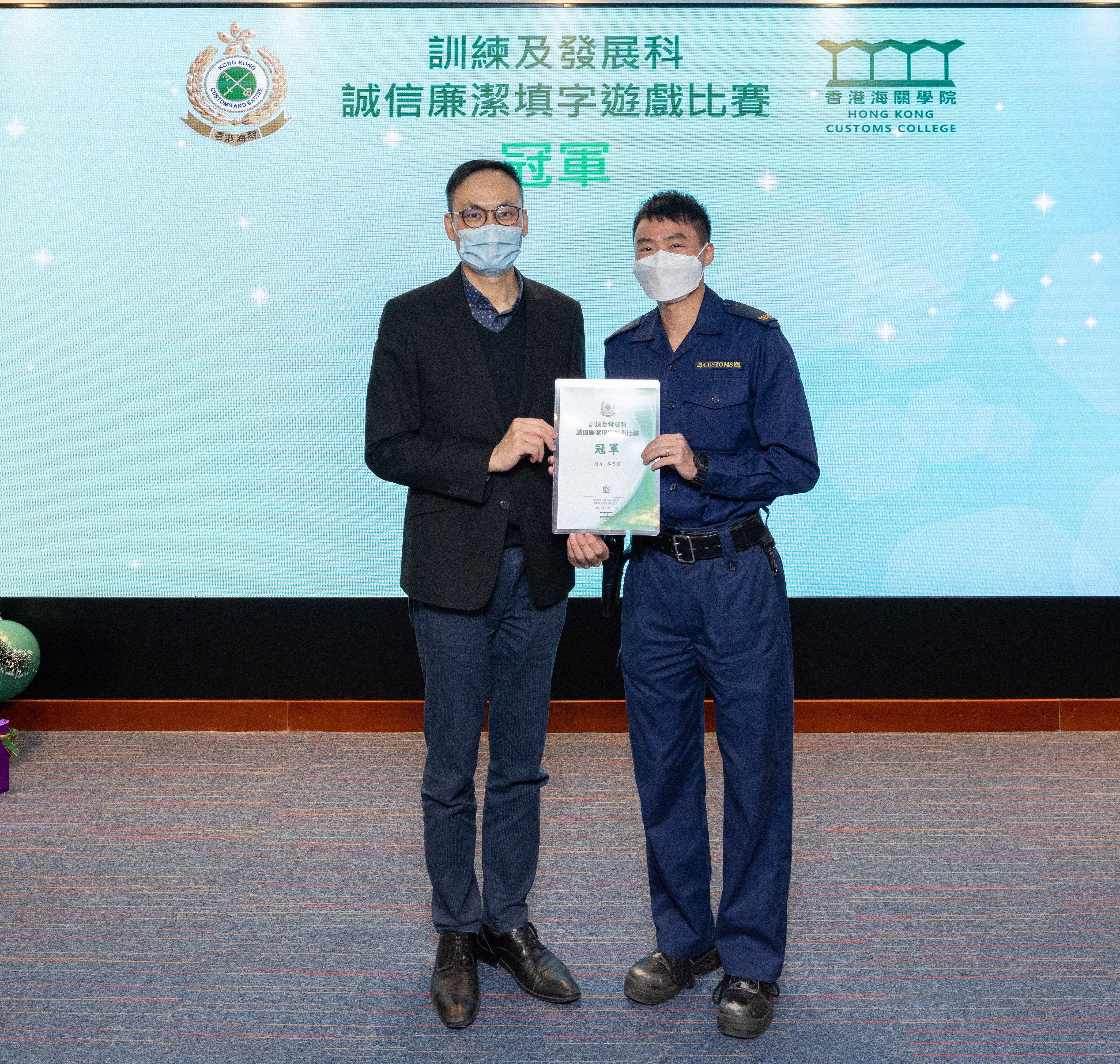 訓練及發展科高級參事黎景豪(左)頒發獎狀予「誠信廉潔填字遊戲比賽」冠軍得主。
