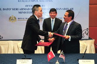 Mr Tang (left) and Dato' Sri Khazali (right), witnessed by Mr Mikuriya (centre), exchange the Mutual Recognition Arrangement document.