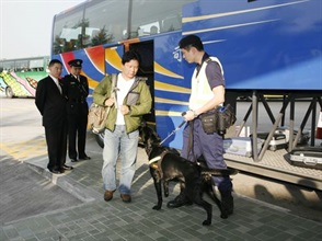 A Customs drug detector dog sniffing a coach passenger for drugs at a demonstration. At the side are the Head of Customs Drug Investigation Bureau, Mr Ben Leung (first left), and the Deputy Head of Land Boundary Command, Mr Chow Chi-kwong (second left), explaining the work of the drug detector dog.