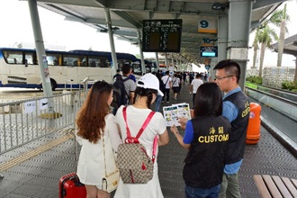 Hong Kong Customs launched an operation code-named "Bullet" today (April 29) to step up consumer protection work during the Labour Day Golden Week period. Photo shows Customs officers at a cross-boundary coach station distributing pamphlets with smart shopping tips to visitors.