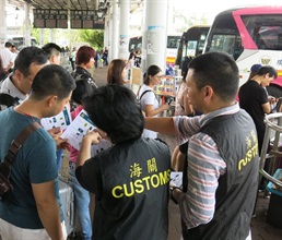 香港海關今日（九月二十八日）展開「極光」行動，在「國慶黃金周」期間加強巡查，以保障消費者。圖示海關人員在過境巴士站派發提醒訪港旅客精明消費的單張。