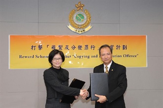 Assistant Commissioner (Intelligence and Investigation) of the Customs and Excise Department, Mr Tam Yiu-keung (right), exchanges the signed agreement on "Reward Scheme to Combat Copying and Distribution Offence" with the Chairman of Hong Kong Copyright Licensing Association, Ms Judy Cheng.