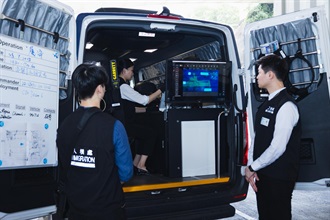 香港海关联同入境事务处及消防处今日（七月二十八日）下午在青衣海关验货场进行代号「履海」的跨部门反恐情报处理及危害物质事故联合演习。图示入境事务处人员出动配备高精密鉴证仪器的流动鉴证战术车，鉴证该怀疑非法入境者所持的旅行证件。