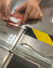 Hong Kong Customs launched a three-month pilot run for the duty stamp system on October 6. Photo shows Customs officer affixing a trial duty stamp to a cigarette package.