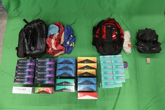 一名三十二歲入境男旅客因處理未完稅香煙，未有向海關人員作出申報，以及進口另類吸煙產品，違反《應課稅品條例》和《進出口條例》，今日（十二月十二日）在西九龍裁判法院被判處監禁四個月和罰款一千元。圖示檢獲的未完稅香煙及另類吸煙產品。