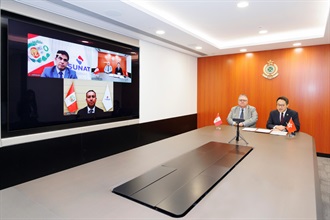 The Commissioner of Customs and Excise, Mr Chan Tsz-tat, concluded the Mutual Recognition Arrangement on Authorized Economic Operator Programme with the National Superintendence of the Customs and Tax Administration (SUNAT) of Peru in hybrid mode at the Customs Headquarters Building today (December 30). Photo shows Mr Chan (right); the Consul-General of Peru, Mr Enrique Carlos Cardenas Arestegui (left); the National Superintendent of Customs and Tax Administration of SUNAT of Peru, Mr Javier Franco Castillo (bottom on the screen); and the Deputy National Superintendent of Customs of SUNAT of Peru, Mr Carlos Adrianzen (top left on the screen), attending the MRA signing ceremony in hybrid mode.