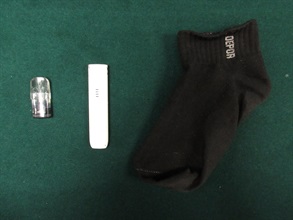 Hong Kong Customs detected a suspected dangerous drugs trafficking case on June 19 at the Lo Wu Control Point. Photo shows a suspected etomidate capsule and an e-cigarette smoking device concealed in a sock.
